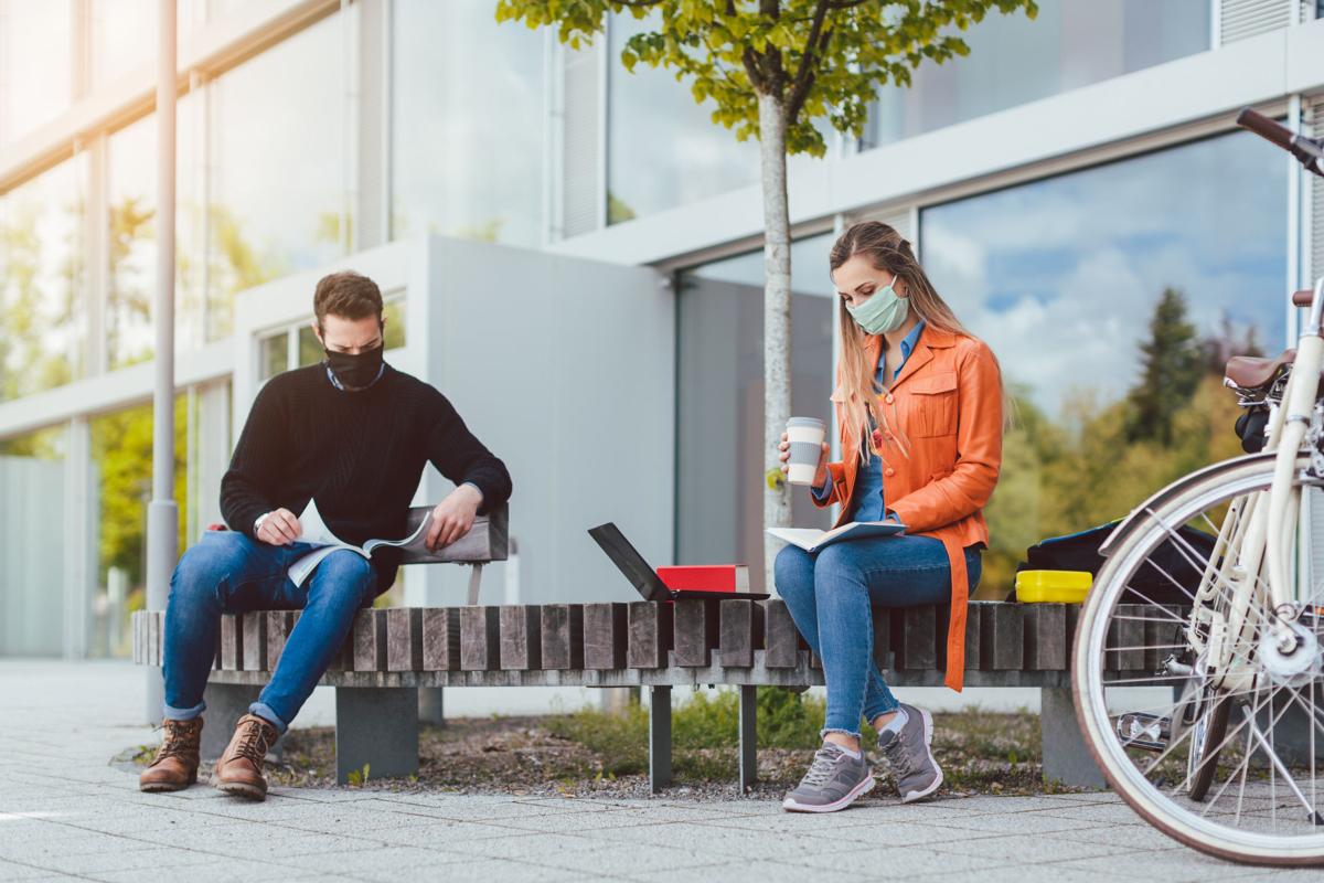 Two college students learning while keeping social distance