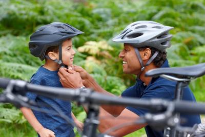 Father helping son put on helmet
