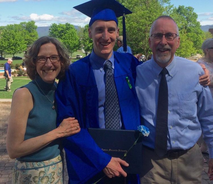 Ryan Gehman poses in his EMU cap and gown with his parents