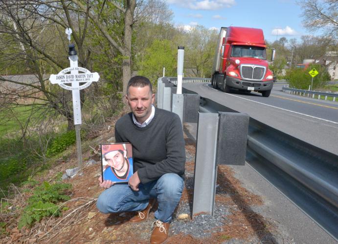 Gary Taft and memorial cross marker he set up along road for son killed in accident