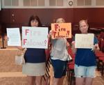 Fire Falconi signs held by Abbie Platt, Suzanne Satterfield, and Jessica Smith