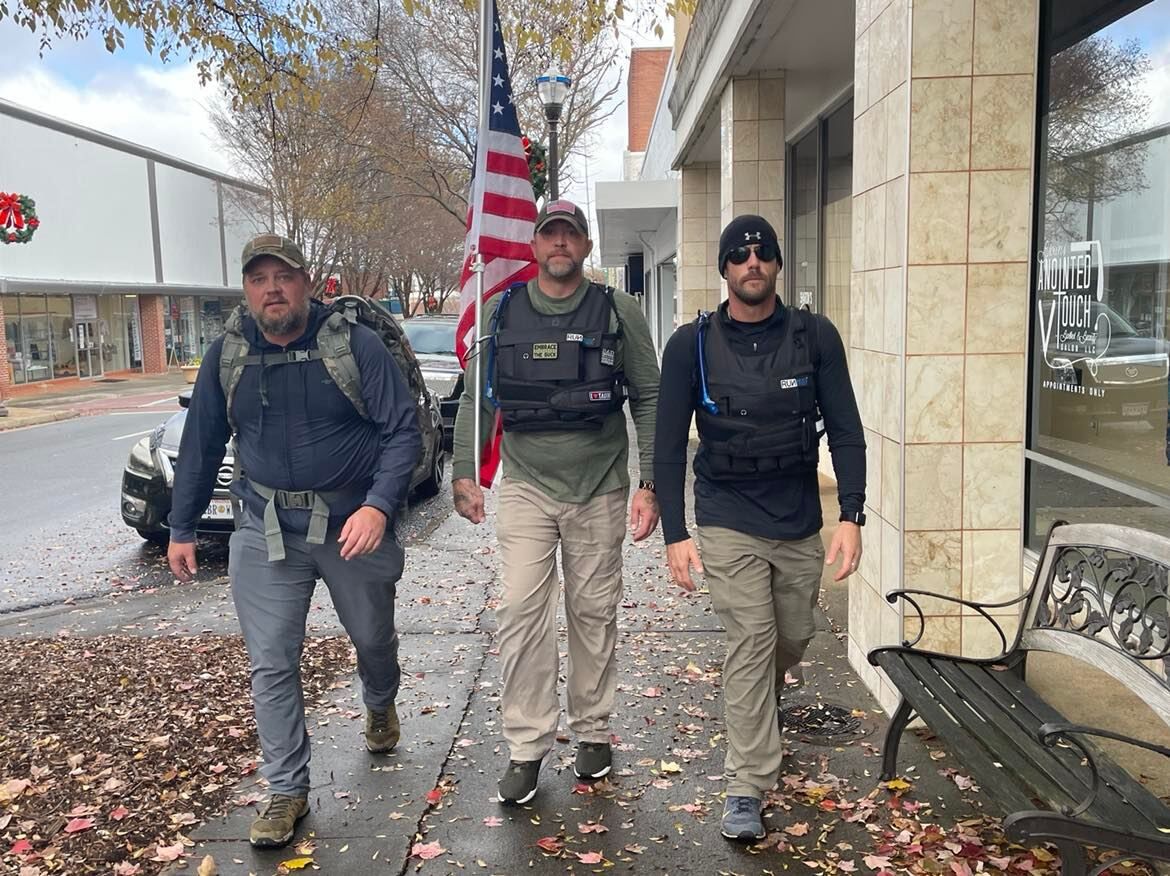 Flanked by supporters, Bender completes the 50 Mile Ruck March