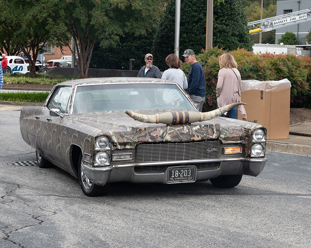 A camouflage Cadillac with bull horns on the front hood was one of the unusual cars driven in to the car show.jpg
