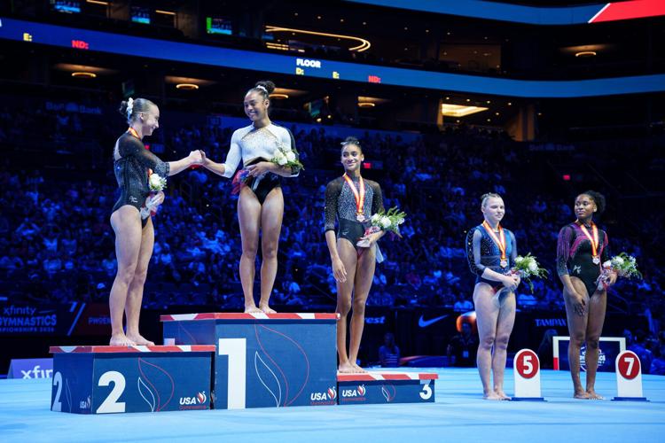 Second- and first-place winners Claire Pease (left) and Hezly Rivera (middle) greet each other on the podium after competing in