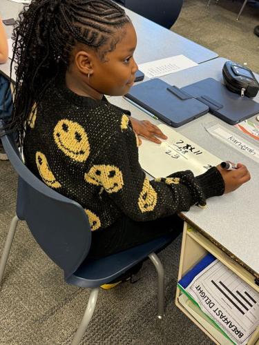 Vinton Elementary fourth grader Kamiyah Thomas uses subtraction to find the difference in the score of a Purdue basketball game on Dec. 8, 2025.