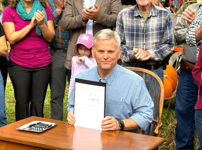 Flanked by supporters, NC Gov. Josh Stein signed a temporary gas tax relief act into law on Oct. 9 at Hickory Nut Gap Farm in Fairview.