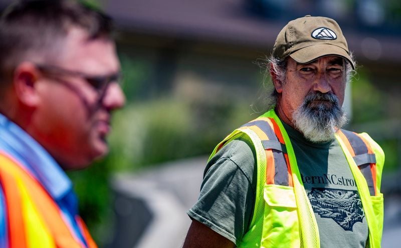 Mike Patton, resident engineer for the North Carolina Department of Transportation Division 14, looks on as NCDOT Division 13 Construction Engineer Nathaniel Moneyham speaks with reporters about ongoing recovery work in Chimney Rock on July 30, 2026.