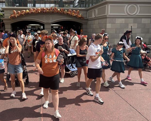 Walt Disney World visitors, some in holiday costumes, work their way into Magic Kingdom theme park for early admittance to Mickey's Not-So-Scary Halloween Party, an after-hours event with exclusive offerings and shows.