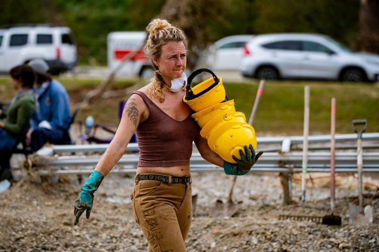 Leah Mangum, an apprentice at the Village Potters Clay Center, brings in hard hats at Riverview Station Friday afternoon as volunteers work to salvage what's left at the art center in the River Arts District in Asheville, following the devastation of Hu...