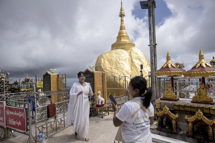 This photo taken on May 28, 2026 shows people posing for photos at the Kyite Htee Yoe Pagoda, also known as the Golden Rock Pagoda, in Mon State.