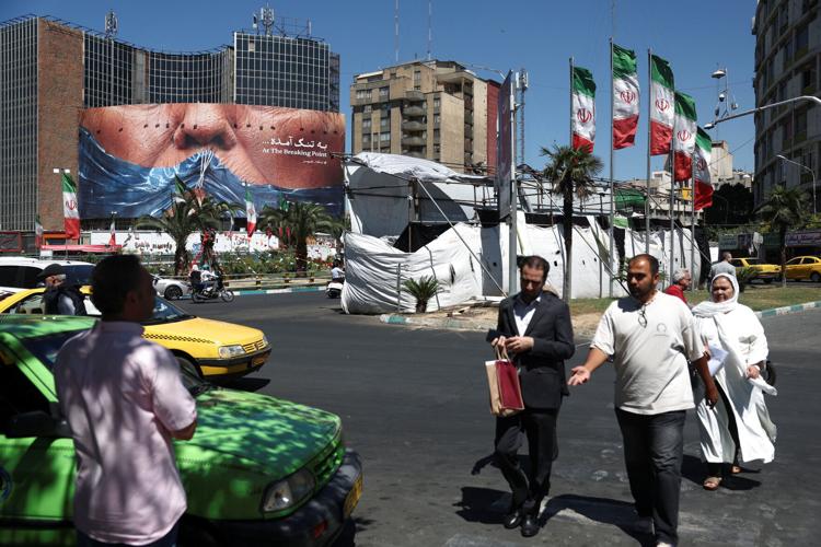 People walk past an anti-U.S. billboard depicting U.S. President Donald Trump and the Strait of Hormuz, in Tehran