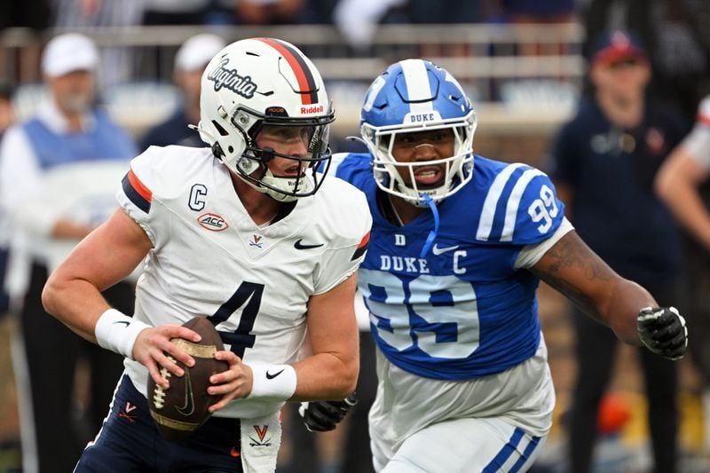 Nov 15, 2025; Durham, North Carolina, USA;  Virginia Cavaliers quarter back Chandler Morris (4) looks for an opening against Duke Blue Devils defensive tackle Aaron Hall (99) during the first quarter at Wallace Wade Stadium. Mandatory Credit: Zachary Ta...