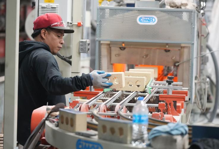 Carlos Rodriguez sets bricks on a line to be warmed for spraying of a colored glaze at Belden Brick in Sugarcreek Ohio.