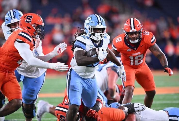Oct 31, 2025; Syracuse, New York, USA; North Carolina Tar Heels running back Demon June (12) runs between Syracuse Orange linebacker David Reese (left) and linebacker Anwar Sparrow (12) in the third quarter at the JMA Wireless Dome. Mandatory Credit: Ma...