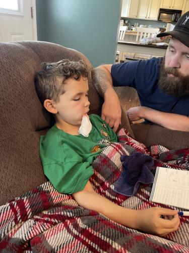 Jonah Reynolds sits with his father in May 2022 after a doctor extracted a tooth that caused him severe pain.