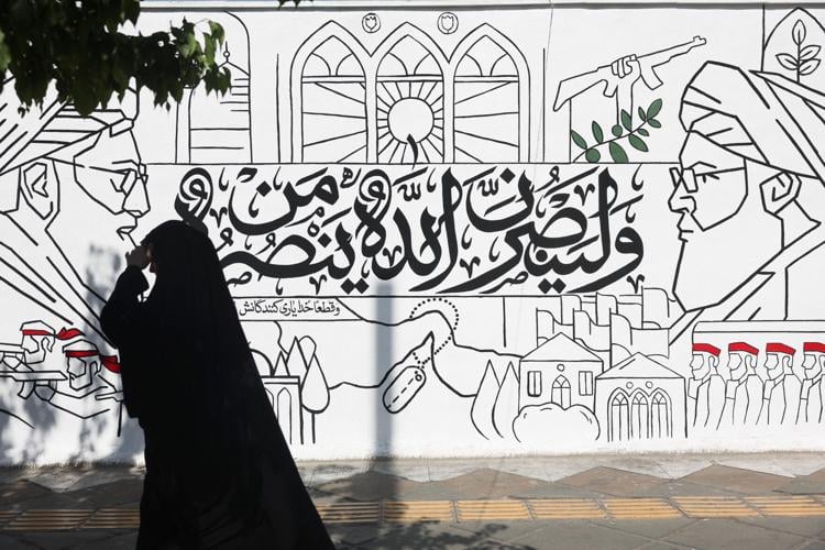 A woman walks past a mural on a street in Tehran