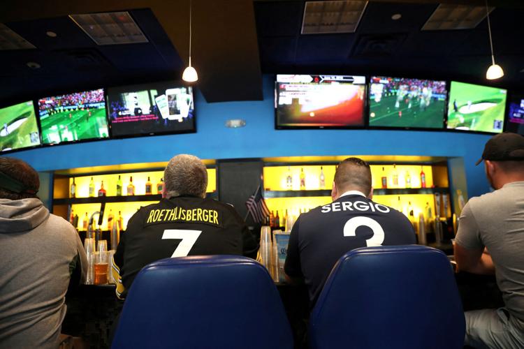 FILE PHOTO: Gamblers watch sports on televisions at Monmouth Park Sports Book by William Hill, shortly after the opening of the first day of legal betting on sports in Oceanport