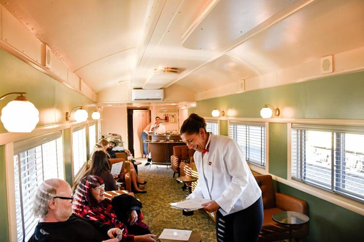 A white-coated server delivers cocktails and snacks to passengers in one of the new cocktail cars offered by Northern California's Skunk Train for short trips from Willits and Fort Bragg on Wednesday, Sept. 16, 2026, in Willits, California.