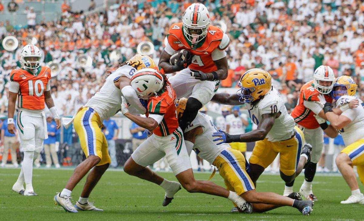 Miami Hurricanes running back Mark Fletcher Jr. leaps over Pittsburgh Panthers defenders during the first half at Hard Rock Stadium in Miami Gardens, Fla., on Saturday, Oct. 24, 2026.