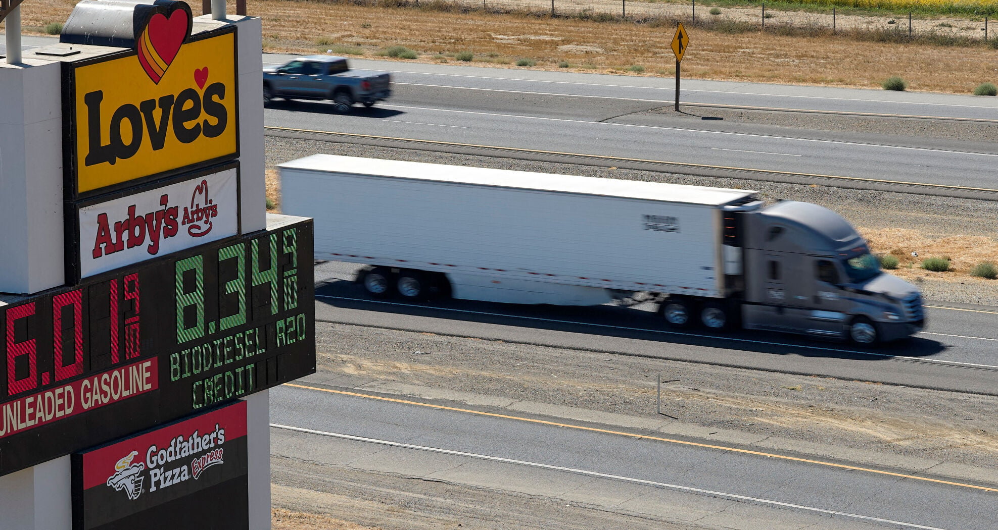 Semi drives past sign showing fuel prices