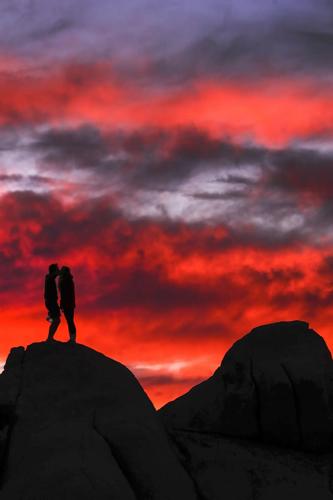 Hikers take in a spectacular sunset on top of rocks