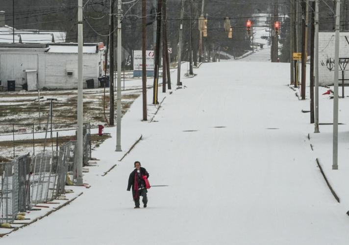 Marni Hoffman walks through a white winter mix on Whitner Street, where traffic is usually steady, in Anderson, SC Sunday, Jan 25, 2026.