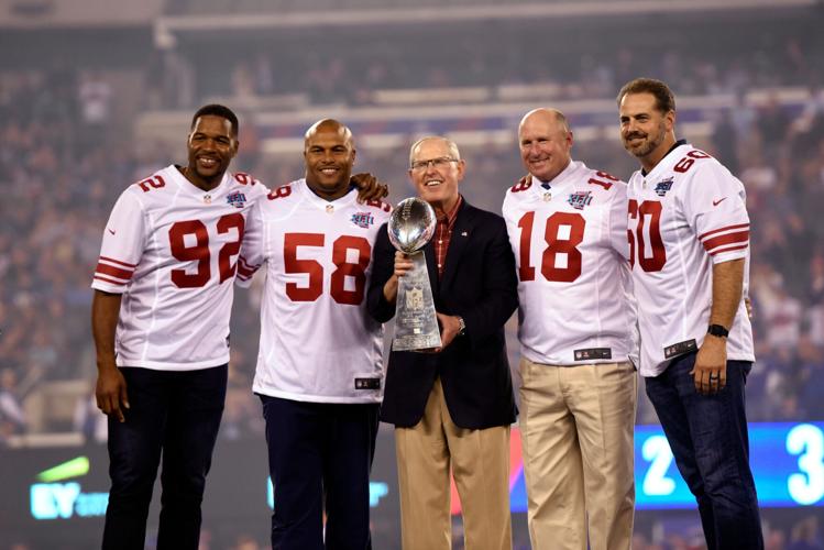Representing the New York Giants team that won the 2007-season Super Bowl XLII are, from left, Michael Strahan, Antonio Pierce, head coach Tom Coughlin, Jeff Feagles, and Shaun O'Hara, standing on the stage during a ceremony as the Giants played the Det...