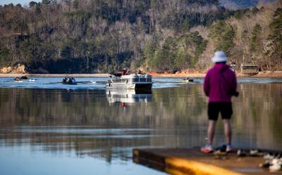 Cooper Rosen, 21, of the University of Rhode Island, stands on a dock as his team returns to shore at Lake Lure March 20, 2026, in Lake Lure, North Carolina. Rosen has been off the water for two weeks with an ACL injury.