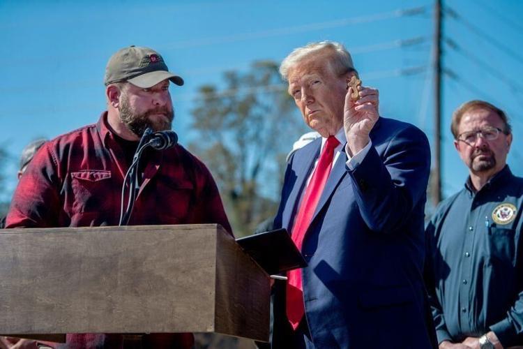 Former President Donald Trump holds up a memento given to him by Adam Smith, creator of Savage Freedom Relief Operations, during his appearance in Swannanoa, October 21, 2024.