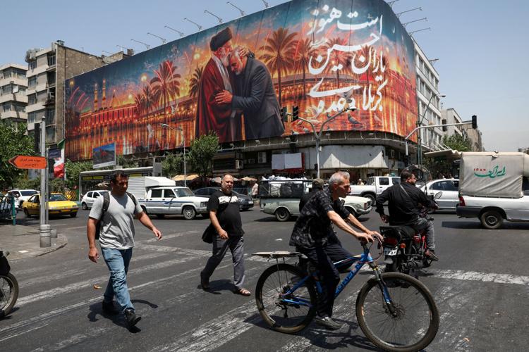 FILE PHOTO: People move past a billboard with an image depicting Iran's late Supreme Leader Ayatollah Ali Khamenei and late senior military commander General Qassem Soleimani, in Tehran