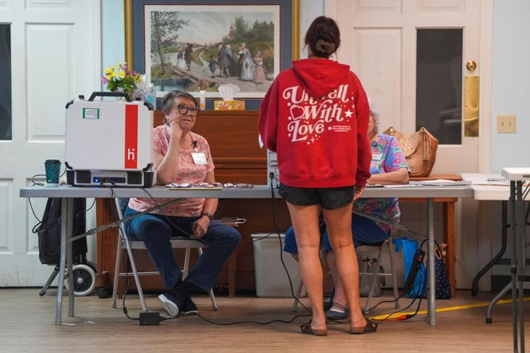 Poll workers listen to a voter at Meridian Baptist Church at 6513 Chapman Highway during the first day of Early Voting in