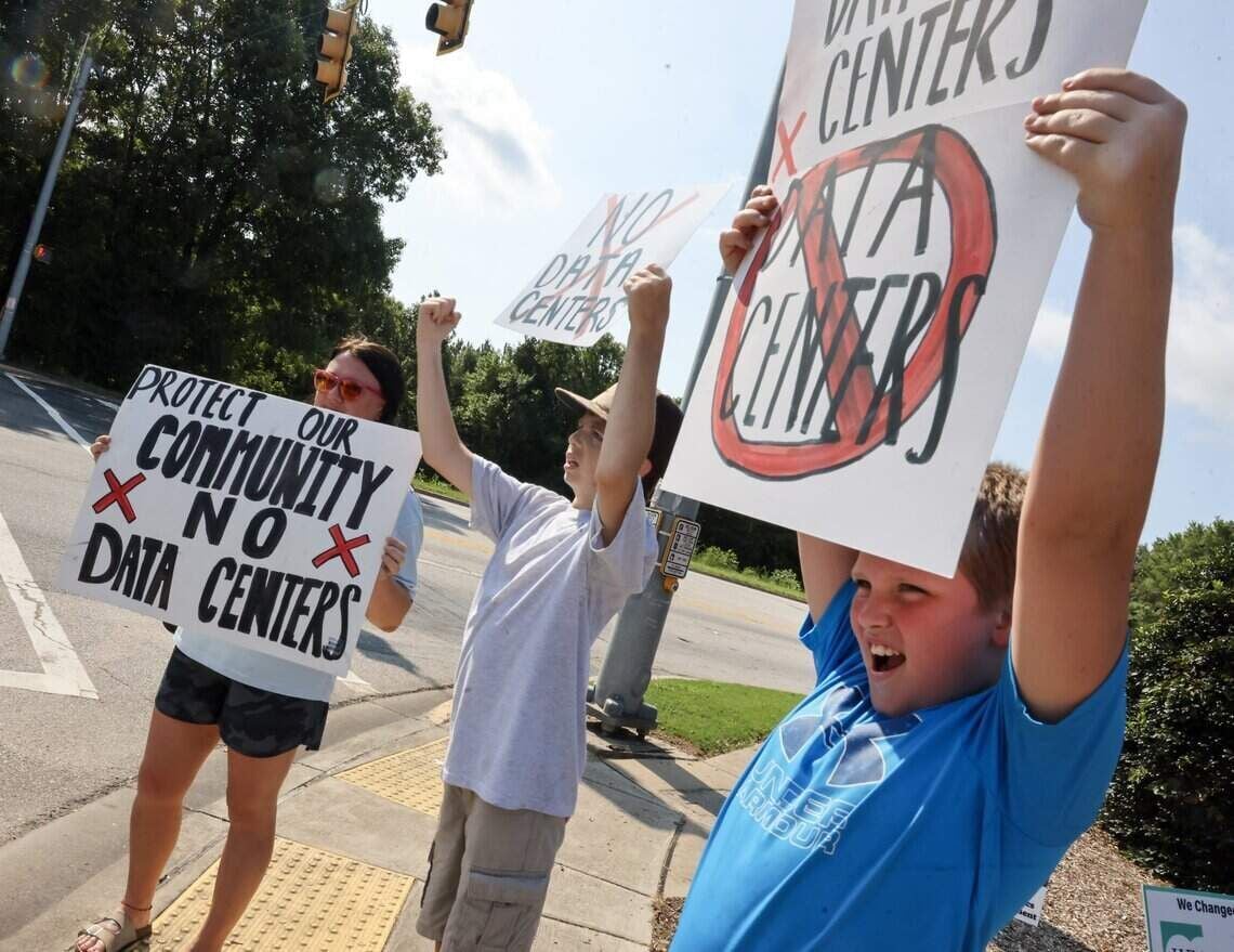 From left, Brittany Barnette, 14-year-old A.J. Barnette and 10-year-old Leo Barnette hold "no data center signs outside the Chester Walmart Saturday, July 18, 2026.