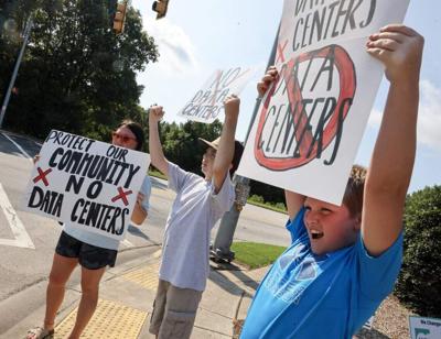 From left, Brittany Barnette, 14-year-old A.J. Barnette and 10-year-old Leo Barnette hold "no data center signs outside the Chester Walmart Saturday, July 18, 2026.