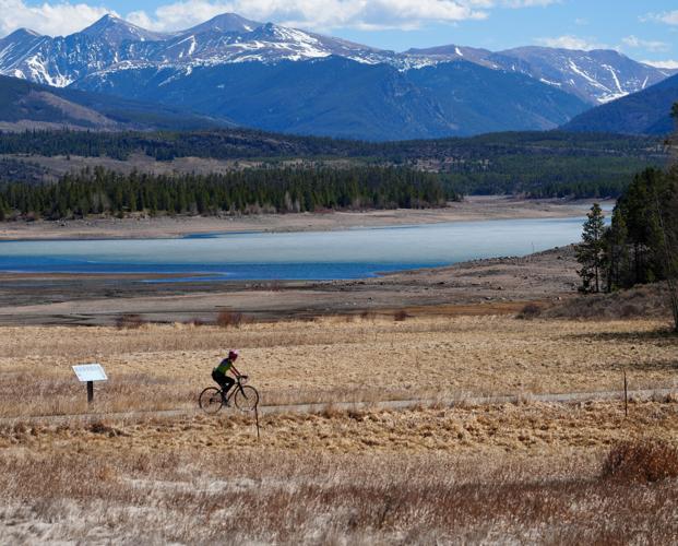 A person rides their bike in front of Lake Dillon in Frisco, Colorado, on March 26, 2026, as the reservoir sits at a low level before spring snowmelt begins refilling it. Water managers fear the poor snowfall this winter means the lake will receive far les