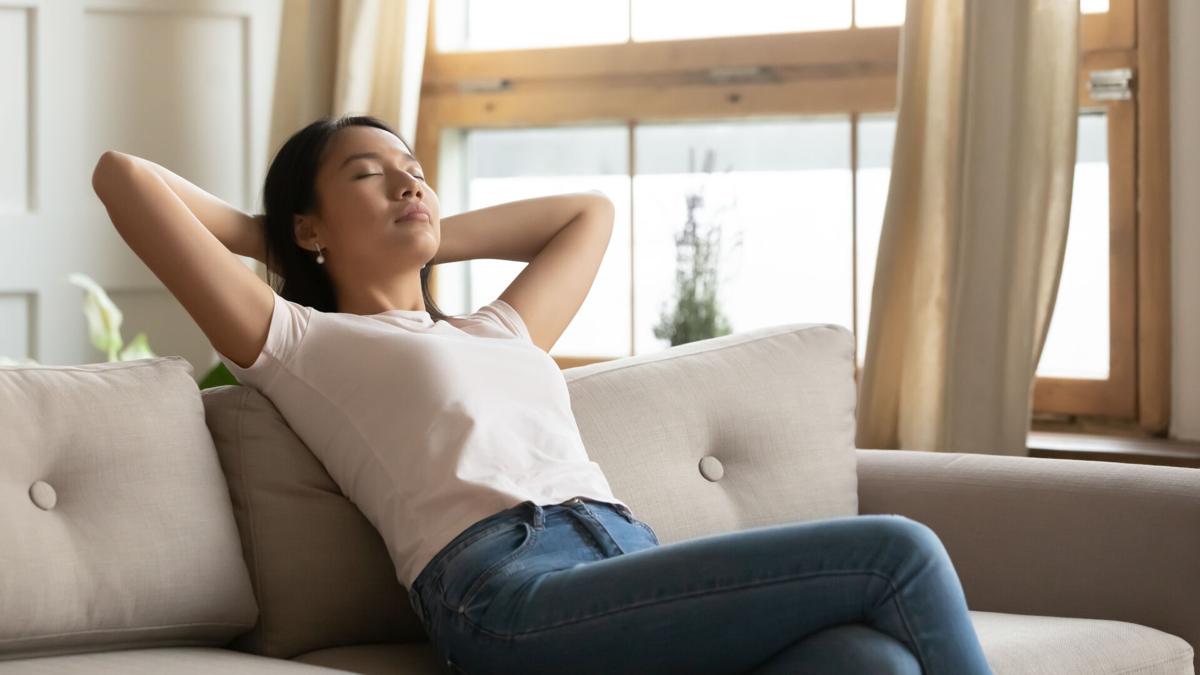Calm Vietnamese girl relax at home couch breathing air
