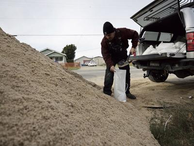 A Seaside resident fills a sandbag before a storm Spanish