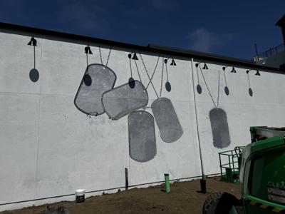 A mural, shown in progress at The Promenade in Marina
