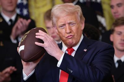 U.S. President Donald Trump holds up a football presented to Trump during a presentation ceremony for the Commander-in-Chief Trophy to the Navy Midshipmen football team in the East Room of the White House on April 15, 2025, in Washington, D.C..
