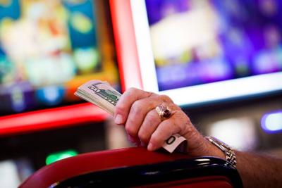 A man holds a stack of money while gambling at a slot machine at Two Kings Casino in Kings Mountain, N.C., Wednesday, June 1, 2022.