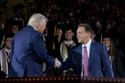 President Donald Trump, left, shakes hands with former Alabama Crimson Tide football coach Nick Saban as Trump takes the stage to address graduating students at Coleman Coliseum at the University of Alabama on May 1, 2025, in Tuscaloosa, Alabama.