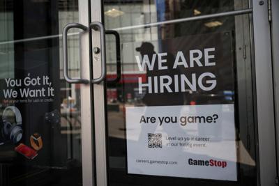 A sign for hire is posted on the door of a GameStop in New York City