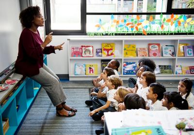 Kindergarten students sitting on the floor listening to teacher