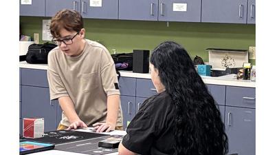 Radley Dean, left, teaches Sophia Kalter how to play “Magic: The Gathering” during one of his club’s meetings at the Festus Public Library, 400 W. Main St.