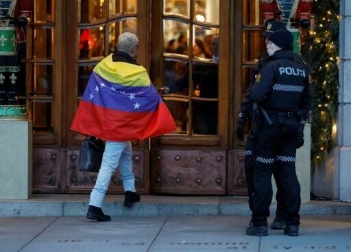 Policemen look on as a man wrapped into a Venezuelan flag enters on December 9, 2025 the Grand Hotel in Oslo, where the Nobel Peace Prize award ceremony is set to take place in the Norwegian capital