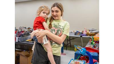 Marina Sarkissian of Festus with her daughter Nora, 2, shop at the yard sale.