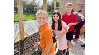 St. Mark’s students, from left, Gavin Richardson, Kinsley Tibbles and Oscar Bates plant seeds in the school’s new garden.