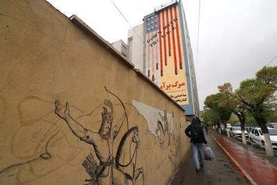 An Iranian walks past an anti-U.S. mural in Tehran on April 5, 2025.