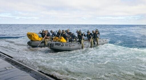 This handout image released by NASA shows US Navy divers preparing to deploy from the well deck of the USS John P. Murtha to recover Artemis II astronauts and the Orion spacecraft after it splashed down in the Pacific Ocean near California