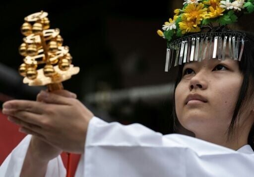 A shrine maiden leads a ceremony as others pray before the start of a procession during the Kanamara festival
