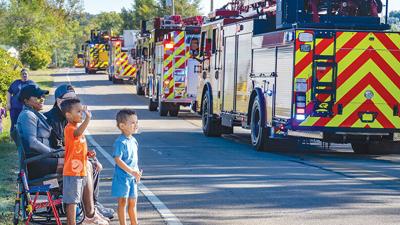 Jazz and Ozzie Packer wave as the fire engine parade drives by in 2025.